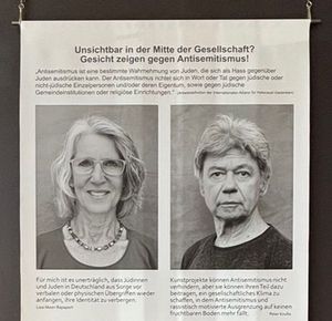 Foto eines Teils eines Informationsaushangs der Ausstellung Unsichtbar – in der Mitte der Gesellschaft? Gesicht zeigen gegen Antisemitismus!, darauf u.a. schwarz-weiß-Porträtfotografien von Lissi Maier-Rapaport und Peter Krullis.