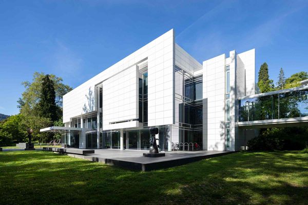Farbfoto des Museums Frieder Burda von außen. Mittig das weiße Gebäude mit davor stehenden Skulpturen; im Vordergrund Rasen, im Hintergrund blauer Himmel und Bäume.
