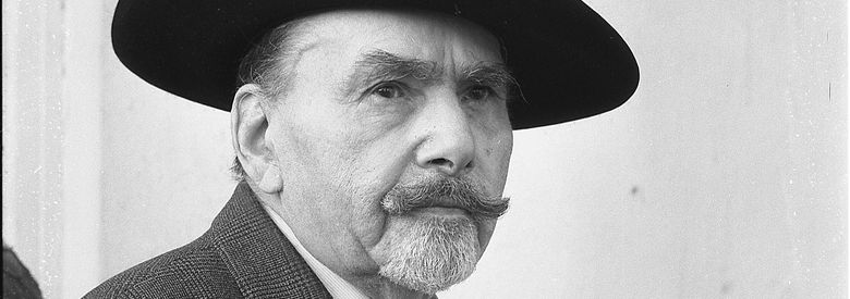 SW-Fotografie von Erwin Sammet. Halbfigur und Halbprofil; in der linken Hand eine Zigarre haltend; einen Hut tragend.