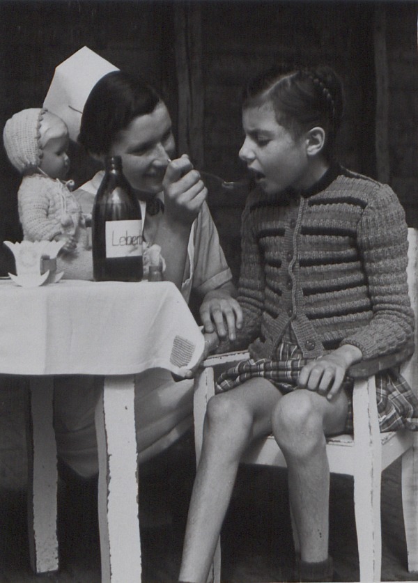 Landeskirchliches Archiv Stuttgart, Kindermedizin P844800010 (Fotograf Hermann Weishaupt): Krankenschwester verabreicht einem Mädchen Lebertran.