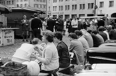Menschen sitzen auf einer Bank am Freiburger Münster.
