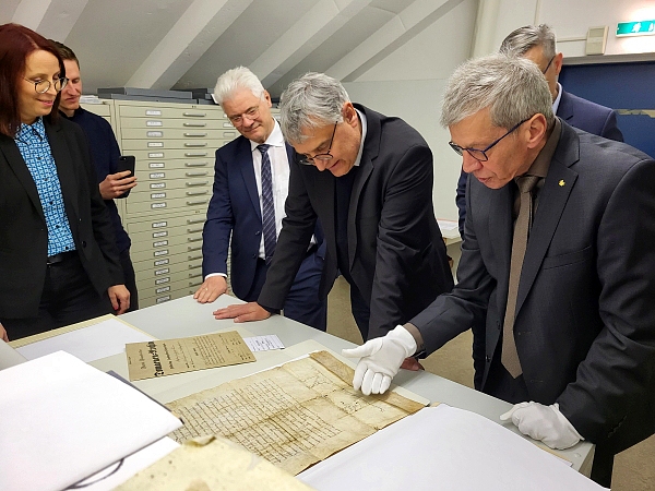 Staatssekretär Arne Braun begutachtet im Kartenmagazin die die älteste im Staatsarchiv verwahrte Urkunde, eine Bleibulle Papst Urbans II. von 1079.